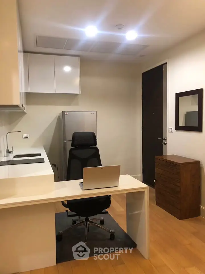 Modern home office with sleek desk, chair, and compact kitchen area, perfect for productivity and convenience.