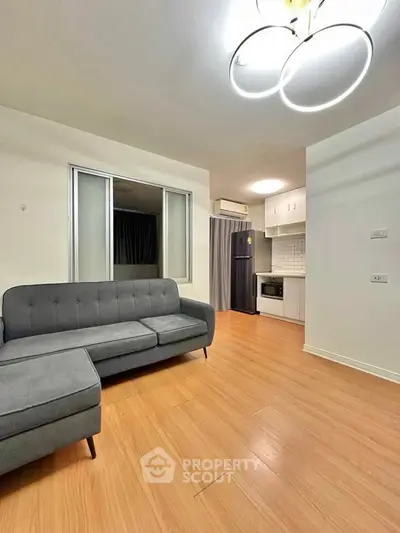 Modern living room with sleek gray sofa and open kitchen layout