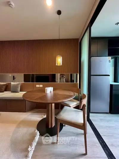 Modern living room with stylish dining area and sleek kitchen featuring a stainless steel fridge.