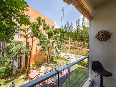 Charming balcony view overlooking lush garden and modern building, perfect for relaxation and outdoor enjoyment.