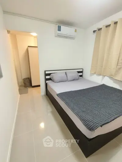 Cozy bedroom with modern decor and air conditioning in a compact apartment.