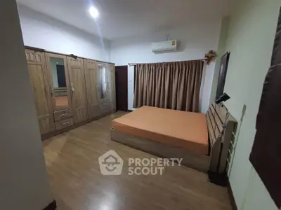 Spacious bedroom with wooden flooring and large wardrobe in modern apartment.