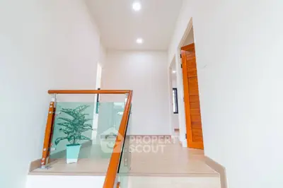Modern hallway with wooden accents and glass railing in a bright home interior