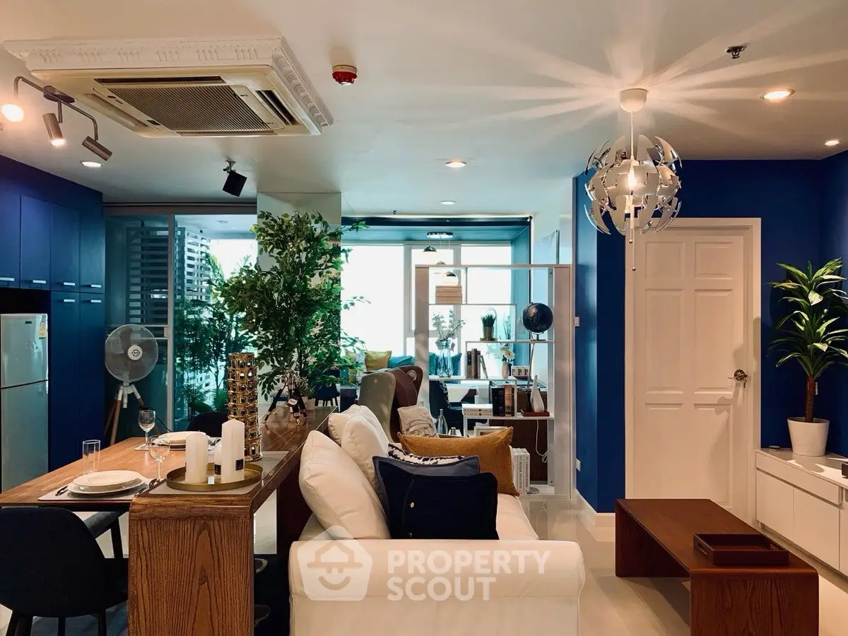 Stylish modern living room with blue accents and natural light, featuring cozy seating and contemporary decor.