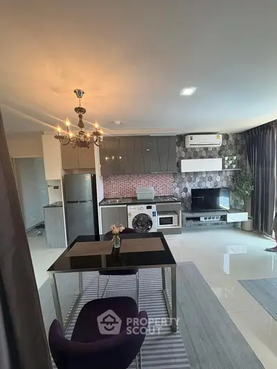Modern open-plan living room with kitchen, featuring sleek appliances and elegant decor.