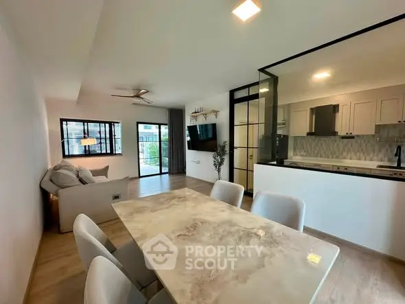 Modern open-layout living and dining area with stylish kitchen and large windows.
