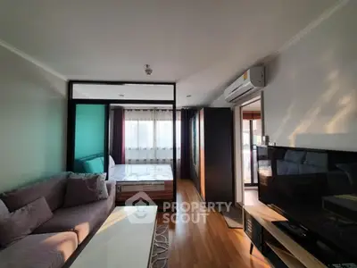 Modern studio apartment with cozy living area and bedroom, featuring wooden flooring and natural light.