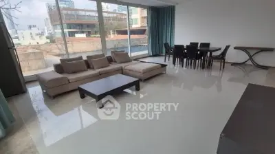 Spacious modern living room with large windows and elegant dining area in a high-rise apartment.