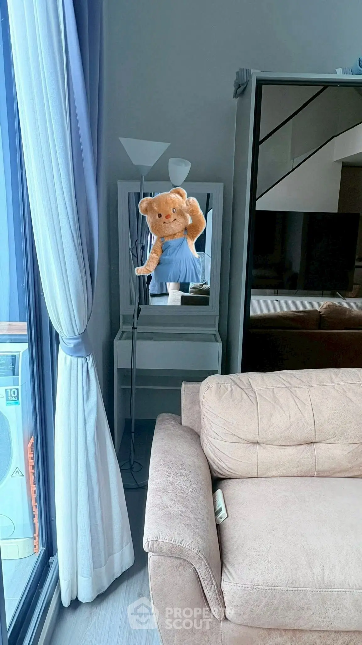 Cozy living room with plush sofa and stylish decor, featuring a unique teddy bear mirror reflection.