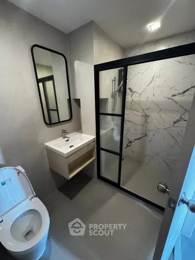 Modern bathroom with sleek shower and stylish vanity in contemporary home.
