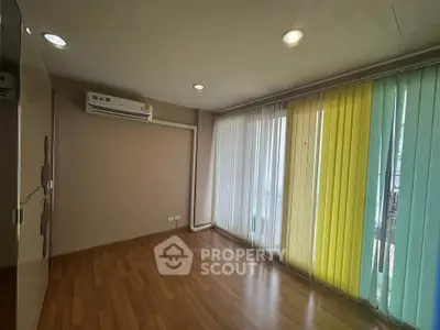 Spacious room with wooden flooring and large windows with colorful blinds, perfect for a bright living space.