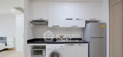 Modern compact kitchen with sleek white cabinets and integrated appliances