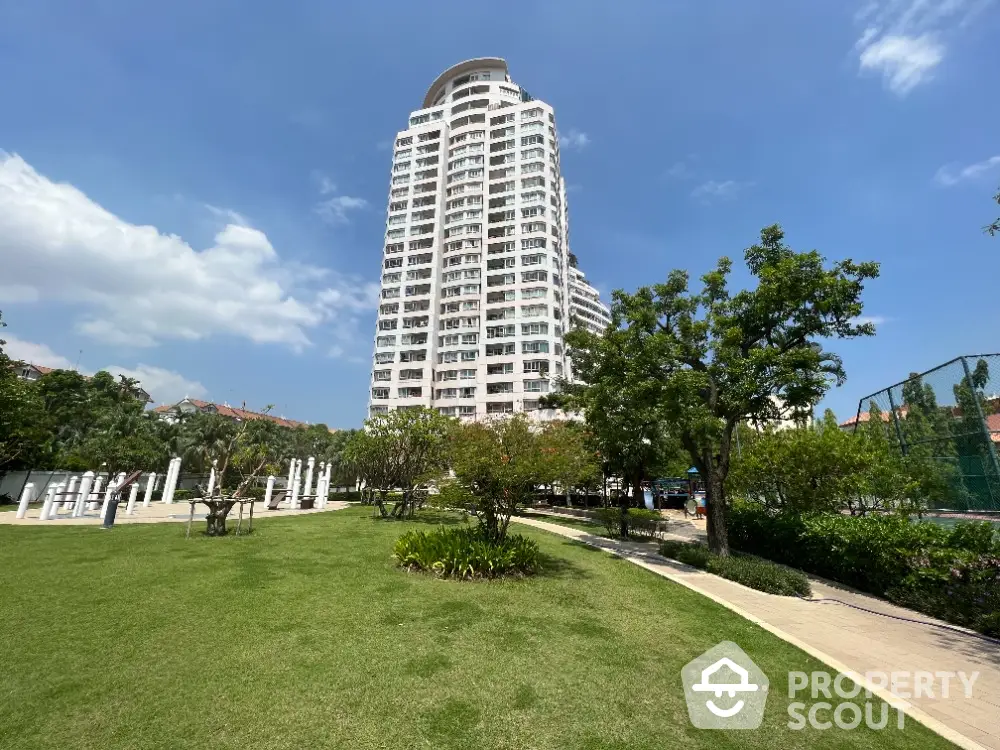 Stunning high-rise building with lush green park and clear blue sky view.