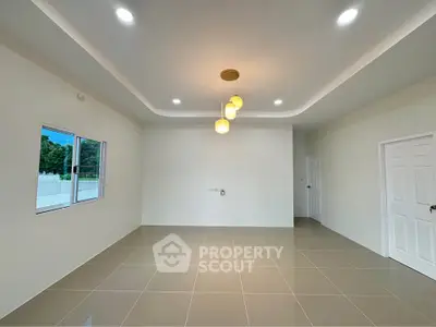 Spacious modern living room with elegant lighting and large window view.