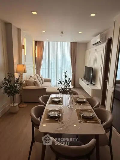 Elegant living room with dining area, modern decor, and large windows offering natural light.