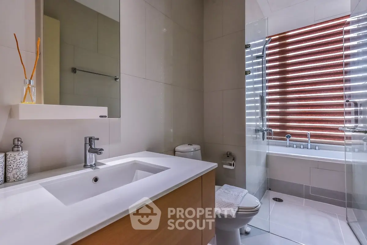 Modern bathroom with sleek fixtures and a glass-enclosed bathtub.