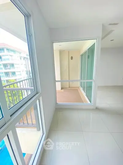 Spacious modern apartment with large windows and balcony view, offering abundant natural light and sleek tile flooring.