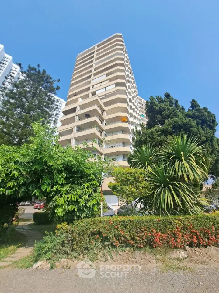 Stunning high-rise building with lush greenery and clear blue sky, perfect for urban living.