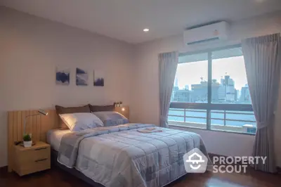 Modern bedroom with city view, featuring cozy bed and large window for natural light.