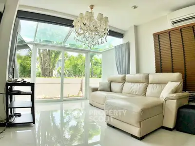Luxurious living room with chandelier and garden view, featuring elegant white sofa and glass ceiling.
