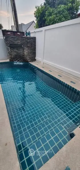 Charming private pool with serene waterfall feature in a modern backyard setting.