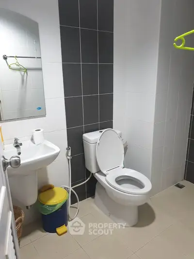 Modern bathroom with sleek tiles and essential fixtures, perfect for a contemporary home.