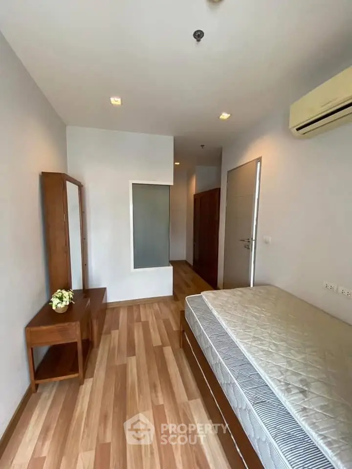 Spacious bedroom with wooden flooring and modern furniture in a stylish apartment.