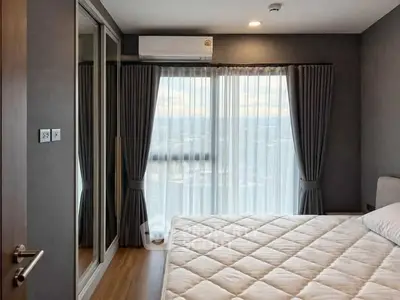 Modern bedroom with large window and elegant curtains, featuring a comfortable bed and mirrored wardrobe.