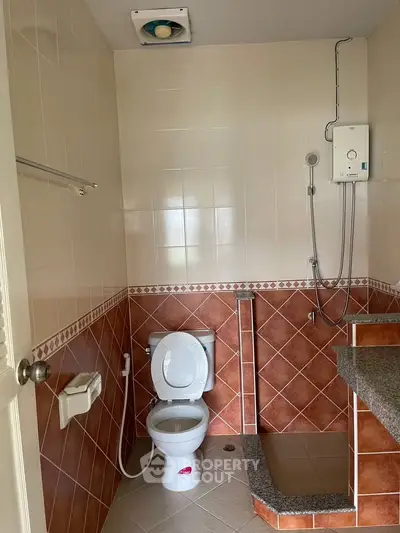 Spacious bathroom with modern fixtures and tiled walls, featuring a shower and toilet in a well-lit setting.