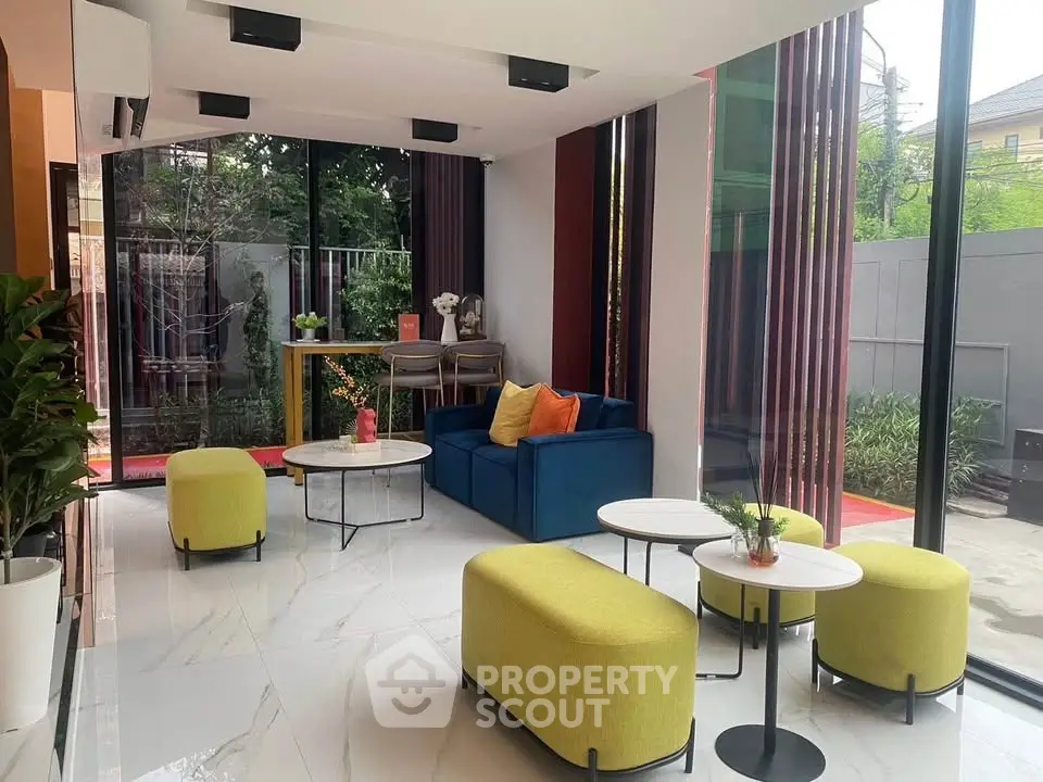 Modern living room with vibrant furniture and large windows overlooking a garden, perfect for relaxation.