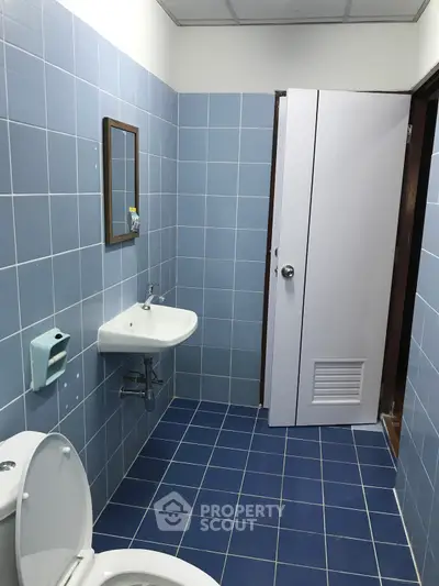 Spacious blue-tiled bathroom with modern fixtures and ample lighting.