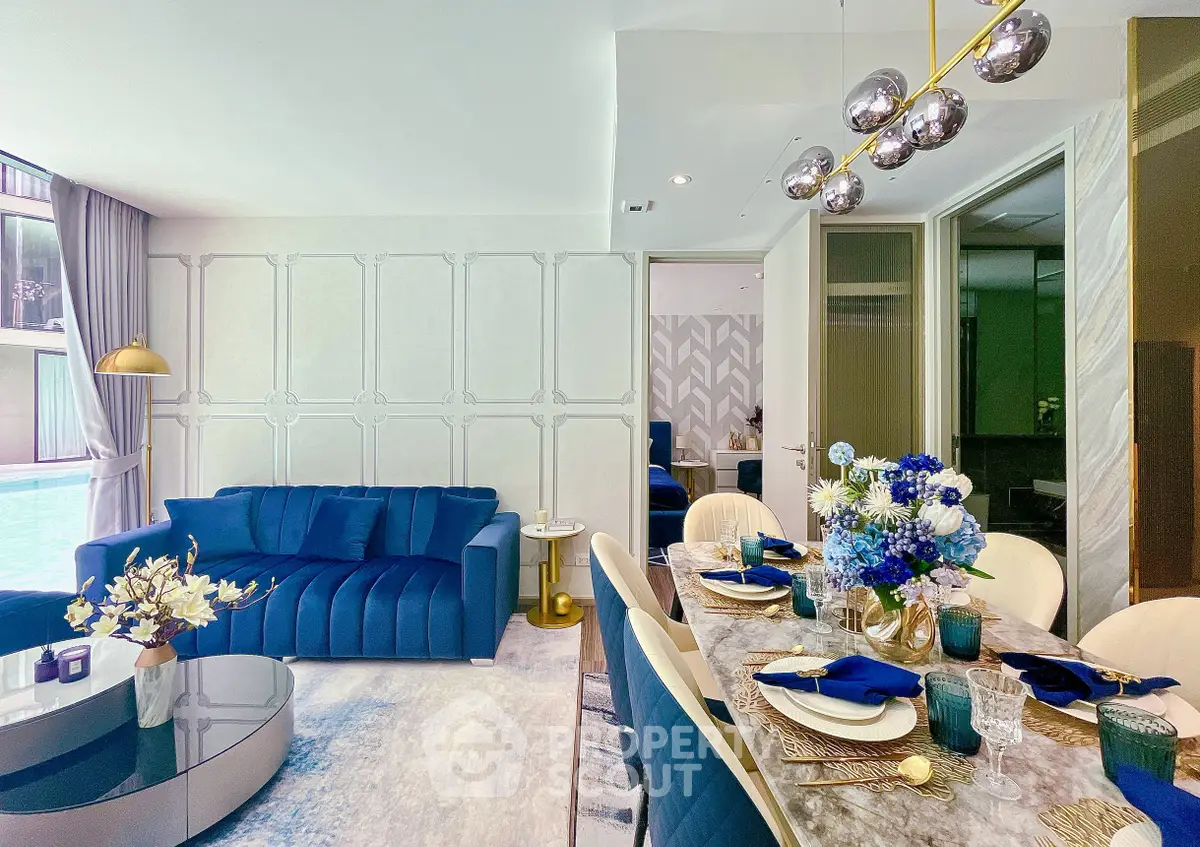 Luxurious modern living room with elegant dining area, featuring plush blue sofa and stylish decor.