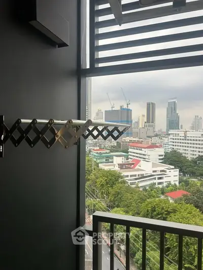 City view from a modern balcony with urban skyline and lush greenery.