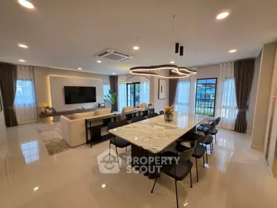 Luxurious open-plan living room with modern dining area and stylish lighting.