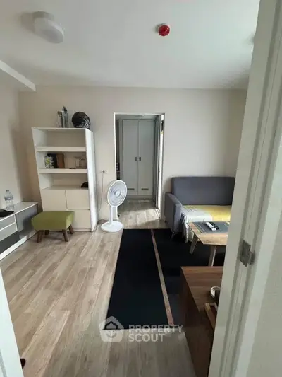Modern living room with stylish decor and wooden flooring, featuring a cozy sofa and sleek shelving unit.