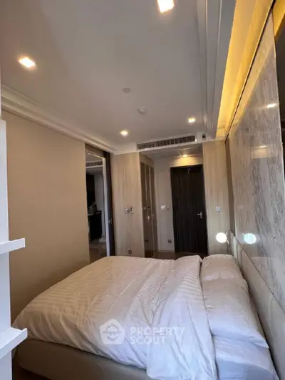 Modern bedroom with elegant lighting and cozy bedding in a stylish apartment.