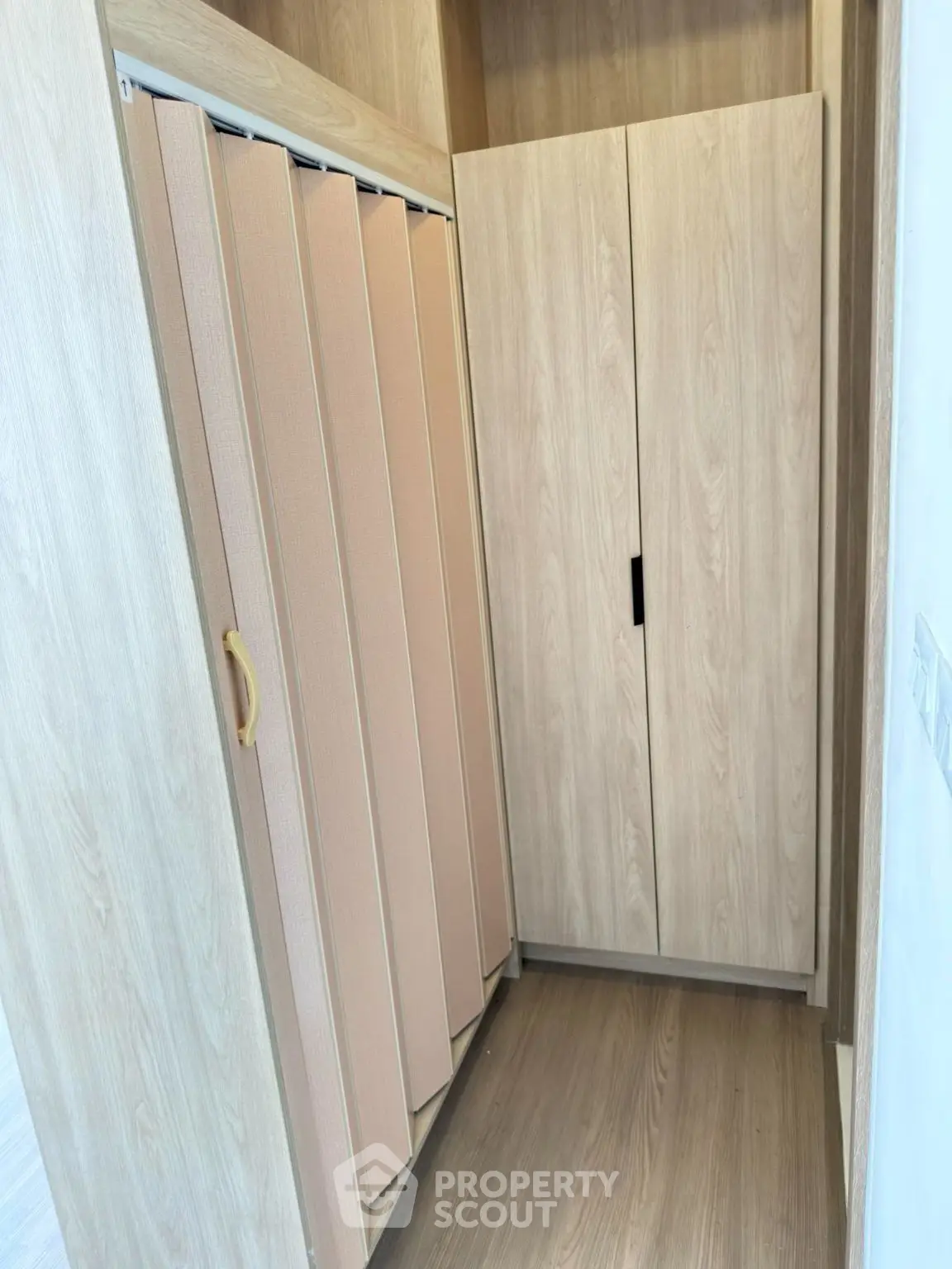 Modern storage space with wooden cabinets and sliding door in a stylish apartment.