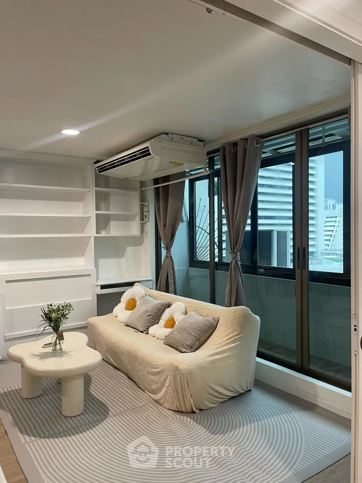 Chic modern living room with cozy sofa, stylish decor, and large windows offering city views.