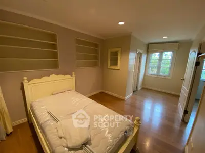 Spacious bedroom with wooden flooring and built-in shelves, perfect for cozy living.
