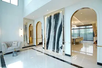 Luxurious modern living room with elegant marble accents and open dining area, featuring high ceilings and large windows.