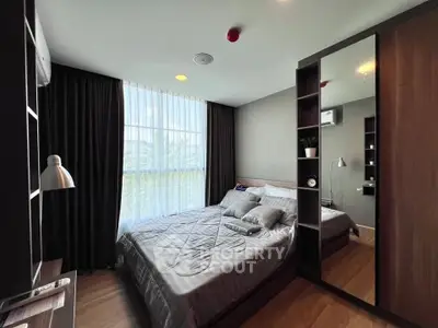 Modern bedroom with stylish decor and large window offering natural light.
