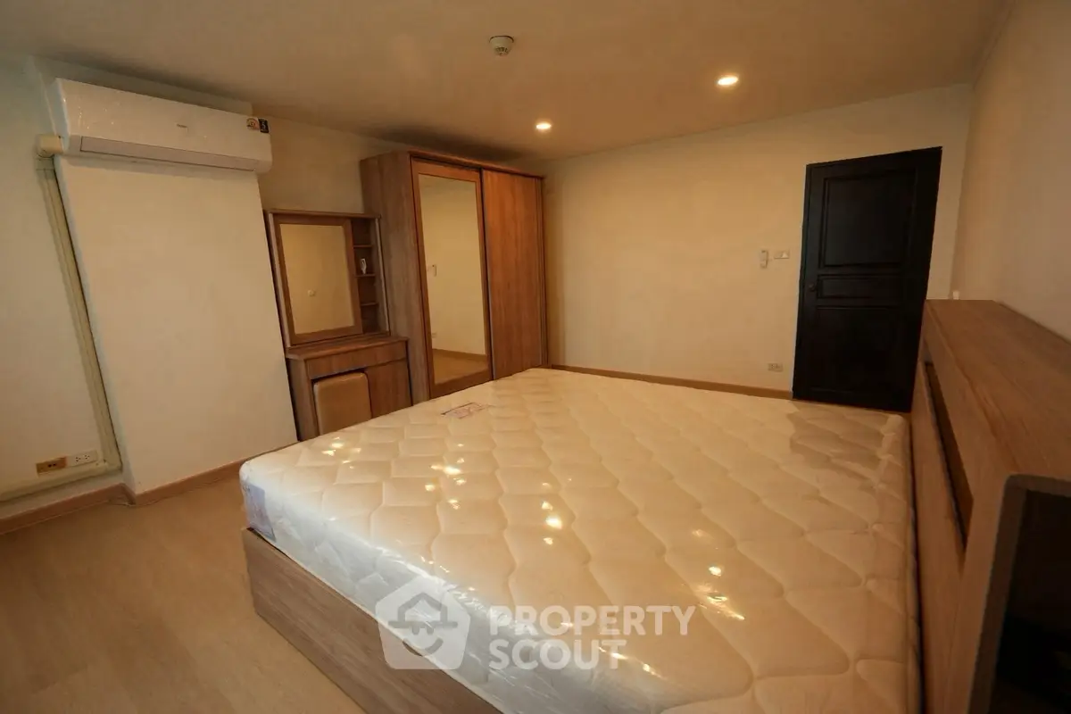Spacious bedroom with modern wooden furniture and comfortable mattress, ideal for restful nights.