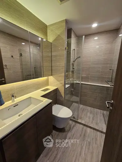 Modern bathroom with sleek design, glass shower, and ambient lighting in luxury apartment.