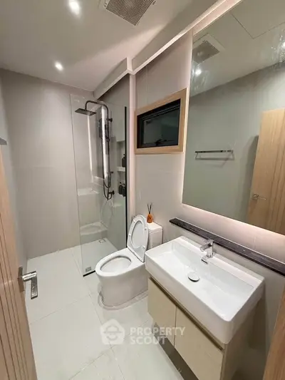 Modern bathroom with sleek fixtures and glass shower enclosure in contemporary apartment.