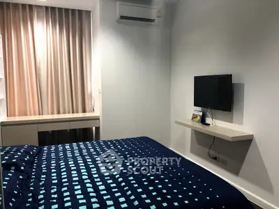 Cozy bedroom with modern decor and wall-mounted TV, perfect for relaxation.