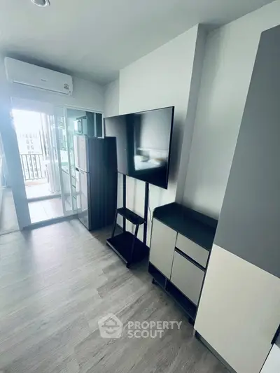 Modern living room with sleek TV stand and balcony view in stylish apartment.
