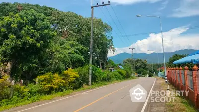 Scenic road view with lush greenery and mountain backdrop, ideal for serene living.