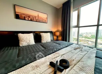 Luxurious bedroom with city view, plush bedding, and elegant decor in modern apartment.