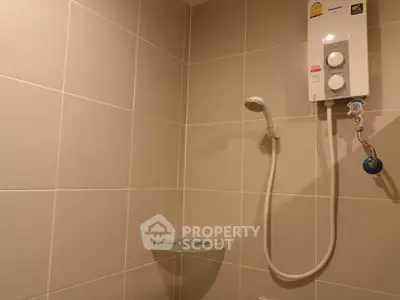 Modern bathroom with sleek shower and water heater in tiled interior.