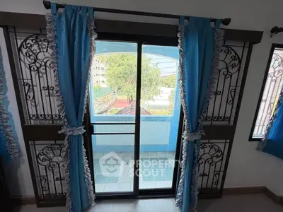 Charming balcony view with elegant blue curtains and decorative ironwork.